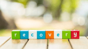 Concept word RECOVERY in colorful tiles for recovery month